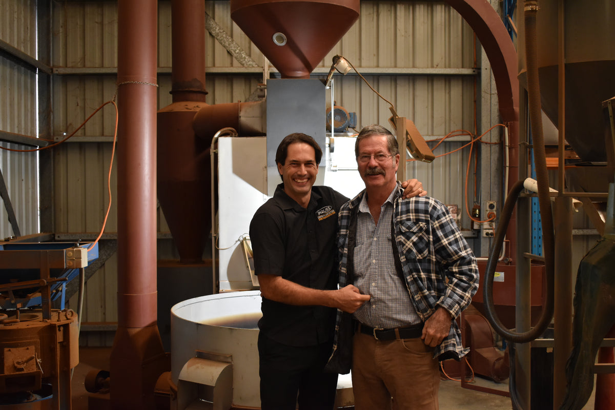 Robert and Nat Jaques standing together in front of the plantation coffee roaster